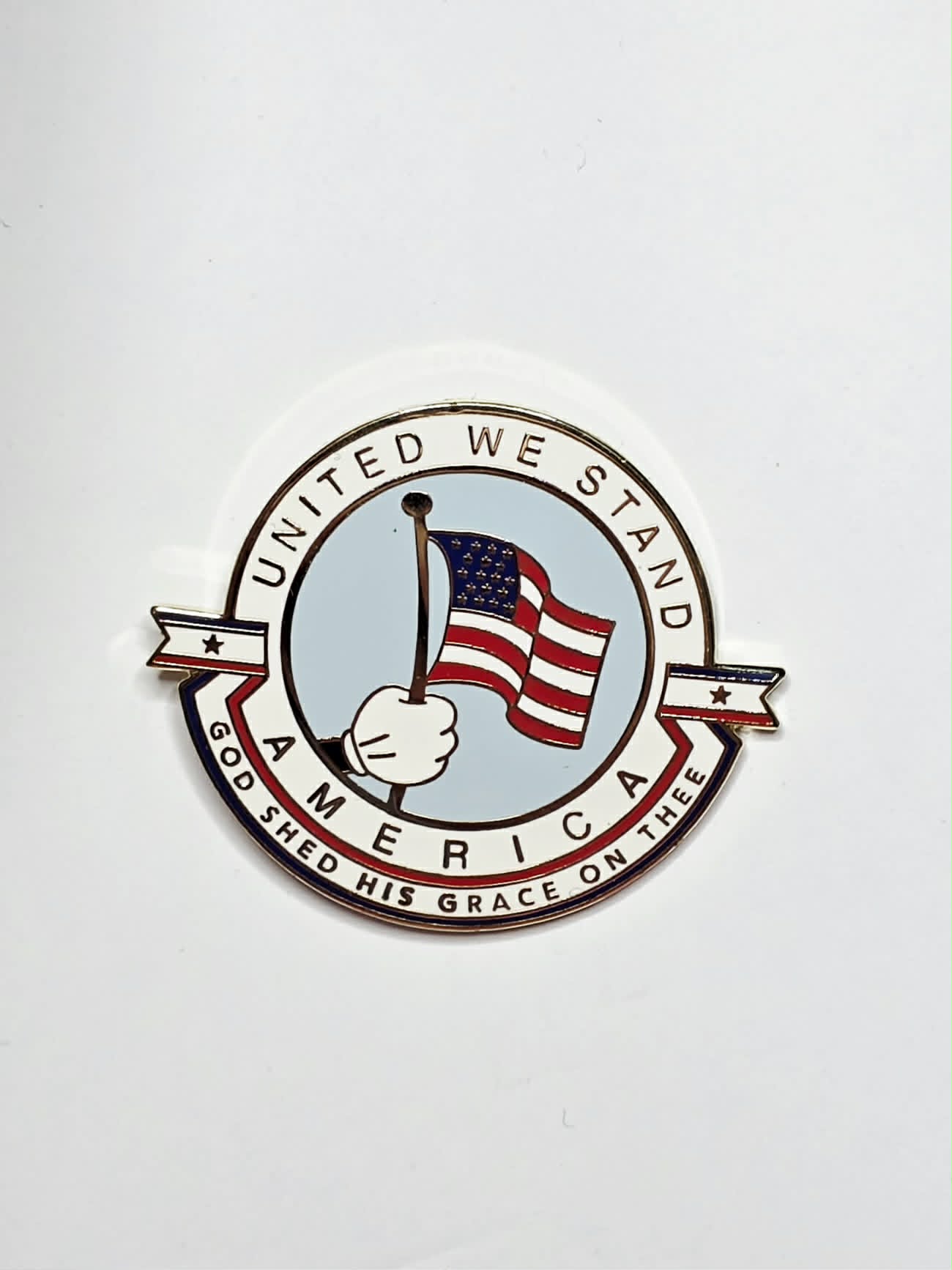 "United We Stand America" collectible pin featuring a patriotic design and gold-tone finish